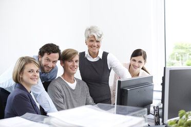 Lächelndes Geschäftsteam bei der Arbeit am Computer im Büro - MFRF000025