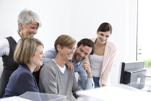 Happy business team at desk in office - MFRF000027