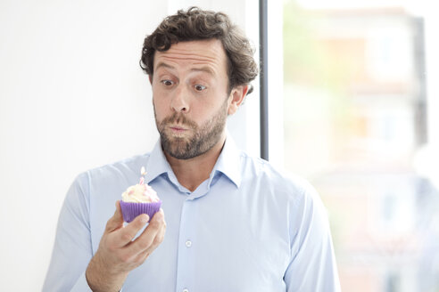Businessman holding birthday cupcake - MFRF000034