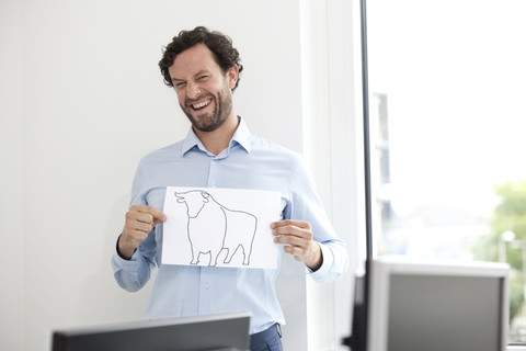 Smiling businessman holding paper with bull figure stock photo