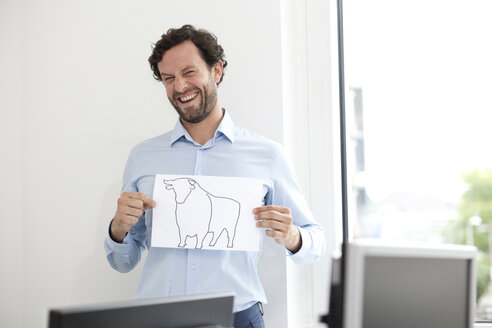 Smiling businessman holding paper with bull figure - MFRF000038
