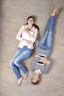 Man and woman lying on floor with laptop and digital tablet - MFRF000048