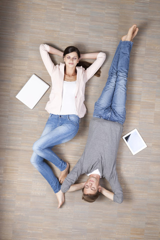 Man and woman lying on floor with laptop and digital tablet stock photo