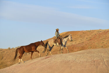 USA, Wyoming, Cowgirl mit zwei Pferden in den Badlands - RUEF001436