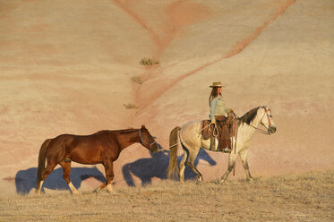 USA, Wyoming, Cowgirl mit zwei Pferden in den Badlands - RUEF001437