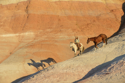 USA, Wyoming, Cowgirl mit zwei Pferden in den Badlands, lizenzfreies Stockfoto