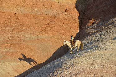 USA, Wyoming, cowgirl riding in badlands at twilight - RUEF001442