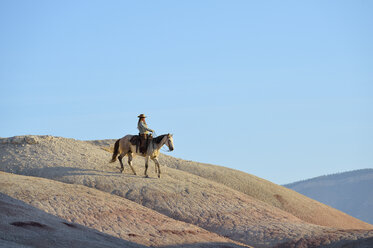 USA, Wyoming, cowgirl riding in badlands - RUEF001443