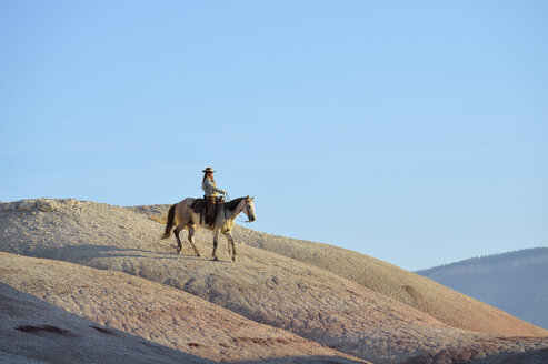 USA, Wyoming, Cowgirl reitet in den Badlands - RUEF001443