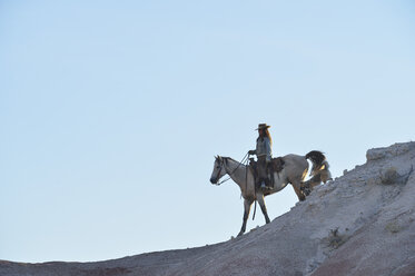 USA, Wyoming, Cowgirl reitet in den Badlands - RUEF001445
