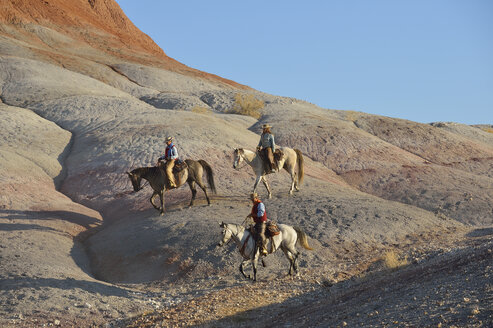 USA, Wyoming, zwei Cowgirls und ein Cowboy reiten in den Badlands - RUEF001449