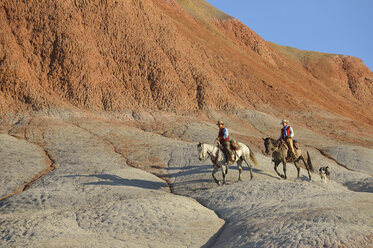 USA, Wyoming, Cowgirl und Cowboy reiten in den Badlands - RUEF001453