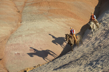 USA, Wyoming, Cowgirl und Cowboy reiten in den Badlands - RUEF001455