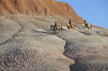 USA, Wyoming, zwei Cowgirls und ein Cowboy reiten in den Badlands - RUEF001464