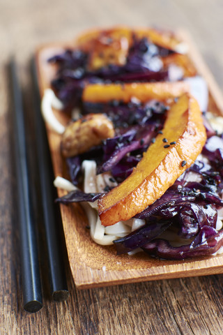 Gebratenes Wintergemüse mit Rotkohl, Winterkürbis und Tempeh auf Nudeln, lizenzfreies Stockfoto