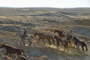 USA, Wyoming, Cowboy und Cowgirl führen Pferde in den Badlands - RUEF001470