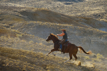 USA, Wyoming, Cowboyreiten in den Badlands - RUEF001477
