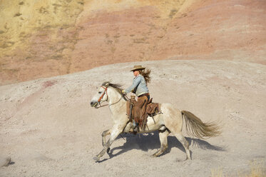 USA, Wyoming, Cowgirl reitet in den Badlands - RUEF001481