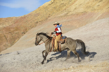USA, Wyoming, Cowgirl reitet in den Badlands - RUEF001482