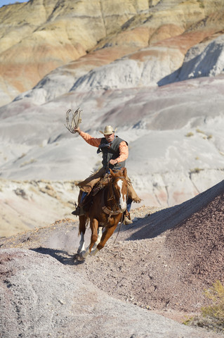 USA, Wyoming, Big Horn Mountains, reitender Cowboy, der das Lasso schwingt, lizenzfreies Stockfoto