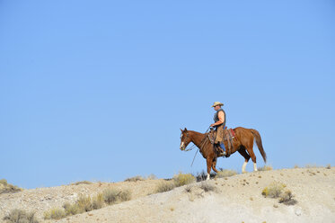 USA, Wyoming, cowboy riding in badlands - RUEF001507