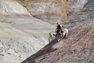 USA, Wyoming, Cowboy reitet abwärts in den Badlands - RUEF001511