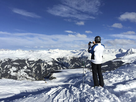 Schweiz, Arosa, Mann fotografiert mit seinem Smartphone - DRF001252