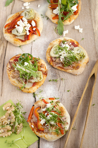 Hausgemachte Mini-Pizzen mit Rucola, Schafskäse, Artischocken, Thunfisch und Tomatensauce, lizenzfreies Stockfoto