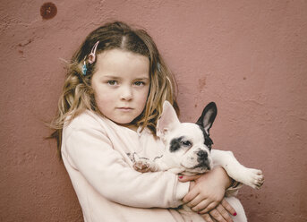 Portrait of girl holding french bulldog puppy - RAEF000031