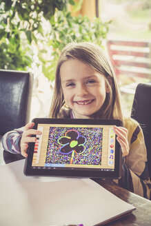 Porträt eines lächelnden kleinen Mädchens, das sein digitales Tablet mit einer Zeichnung zeigt - SARF001306