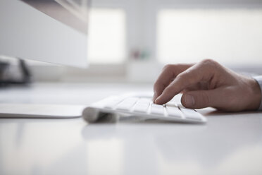 Männerhand tippt auf der Tastatur eines Computers - RBF002448