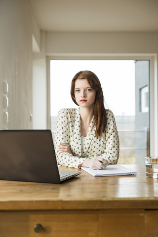 Junge Frau mit Laptop am Holztisch, lizenzfreies Stockfoto