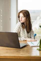 Young woman with laptop at wooden table - UUF003211