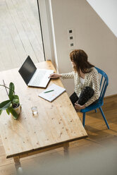 Junge Frau mit Laptop am Holztisch - UUF003215