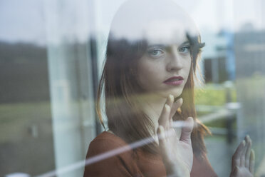 Serious young woman behind windowpane - UUF003223