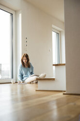 Young woman sitting on floor taking notes - UUF003248