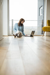 Young woman sitting on floor using laptop - UUF003249