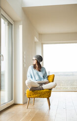 Young woman sitting on chair with digital tablet - UUF003238