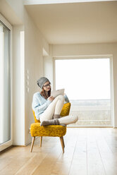 Young woman sitting on chair using digital tablet - UUF003239