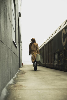Junge Frau mit Koffer auf dem Bahnsteig - UUF003256