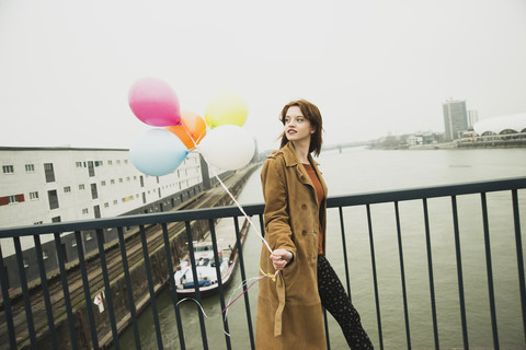 Junge Frau auf einer Brücke mit einem Bündel Luftballons, lizenzfreies Stockfoto