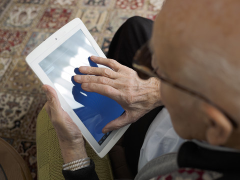 Alter Mann zu Hause mit digitalem Tablet, lizenzfreies Stockfoto