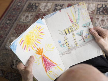 Alter Mann zu Hause betrachtet die Zeichnung eines Kindes - LAF001320