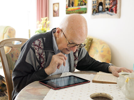 Alter Mann sitzt am Tisch und benutzt ein digitales Tablet - LAF001308