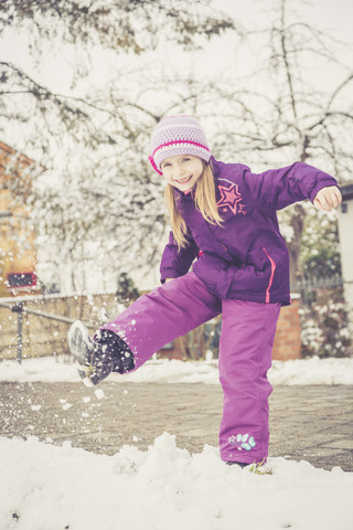 Lächelndes kleines Mädchen, das Schnee tritt, lizenzfreies Stockfoto