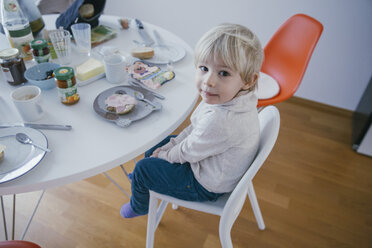 Little boy sitting at breakfast table looking up - MFF001462