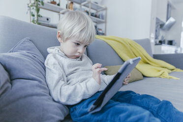 Little boy sitting on the couch playing with digital tablet - MFF001466