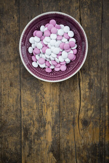 Schale mit rosa und weißen Schokoladenknöpfen auf Holz - LVF002741