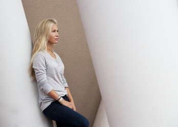 Bblond female teenager leaning on concrete column - WWF003746