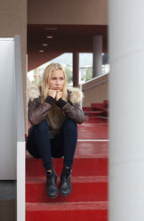 Porträt eines traurigen blonden Teenager-Mädchens, das auf einer Stufe sitzt - WWF003751